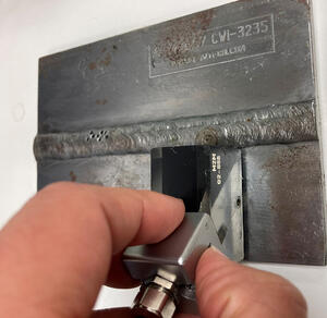 NDT technician scanning a weld plate with ultrasonic probe for surface crack detection using TFM and ECA techniques